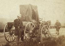 Famed Civil War photographer Alexander Gardner sits beside a traveling darkroom holding a camera lens, Fort Riley, Kansas, 1867. (Library of Congress Prints and Photographs Division)