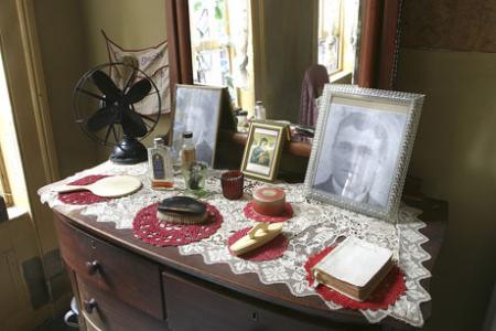 Period dresser in the restored Baldizzi apartment with photographs of Adolpho Baldizzi's parents, hair brushes, and picture of Madonna and child. (Photography by Battman Studios) Period dresser in the restored Baldizzi apartment with photographs of Adolpho Ba