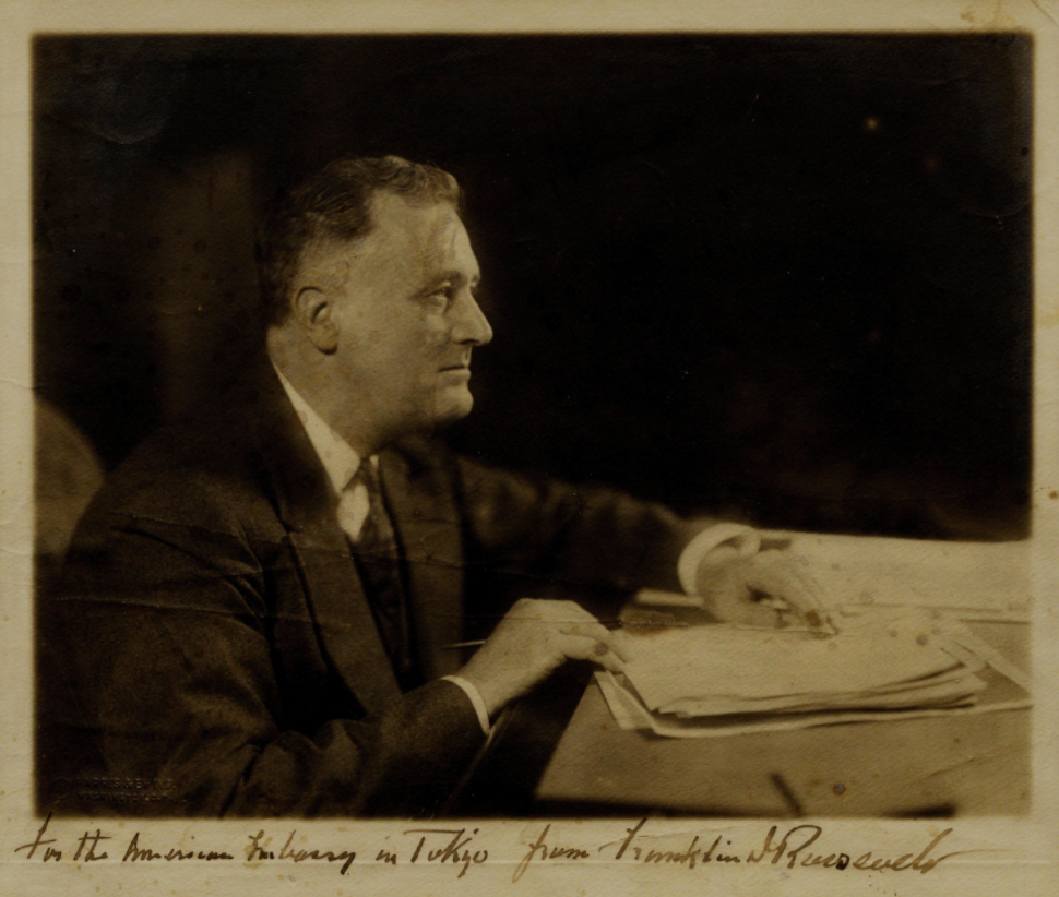 The Great Depression and the New Deal (Side profile photo of Franklin D. Roosevelt sitting at a desk, holding papers)