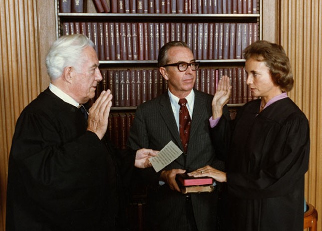 Chief Justice Warren E. Burger administers the Judicial Oath to Judge Sandra Day O’Connor while her husband, John J. O’Connor III, holds the family Bibles, 1981. (Photograph by Michael Evans, The White House)