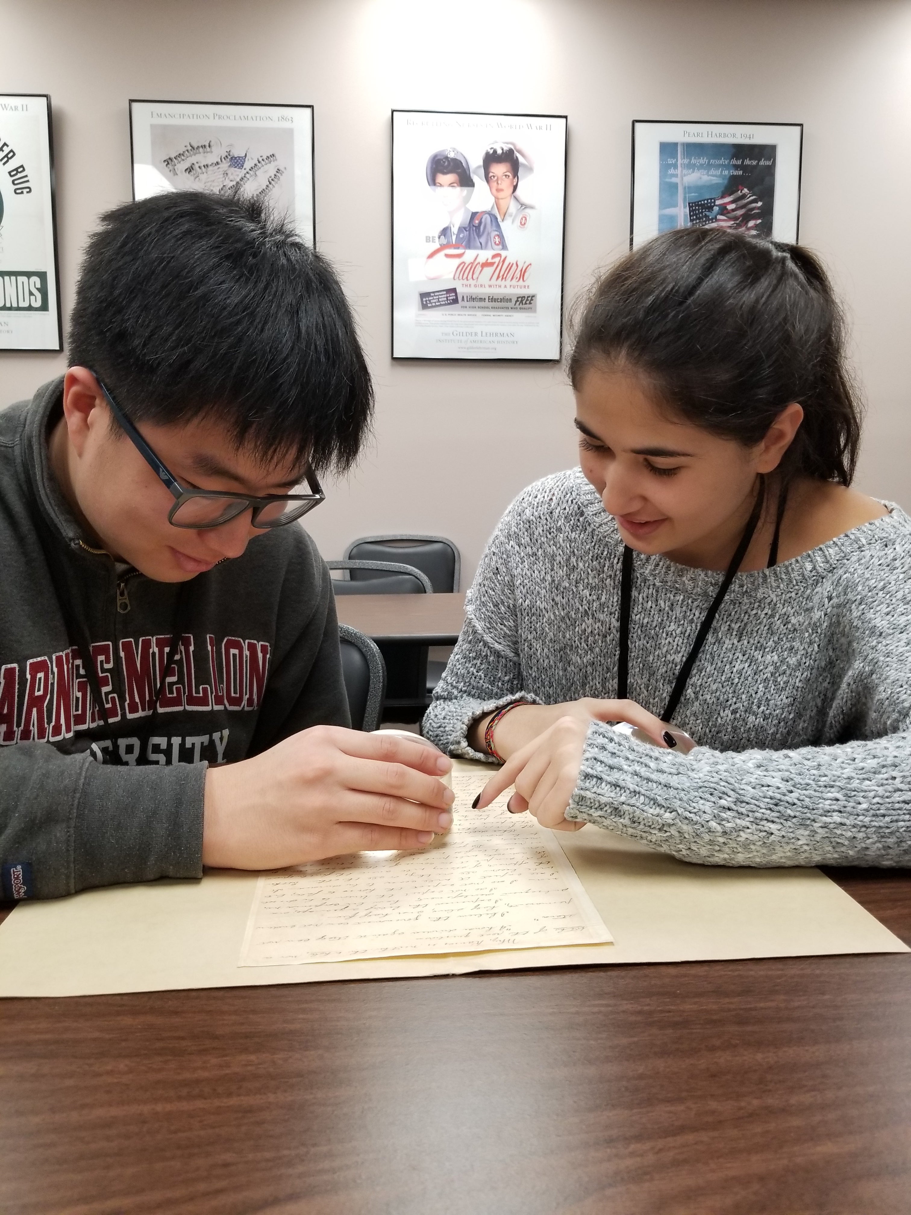 Student interns Jae Joon Lee and Zoubida Bicane examine a document from the Collection.