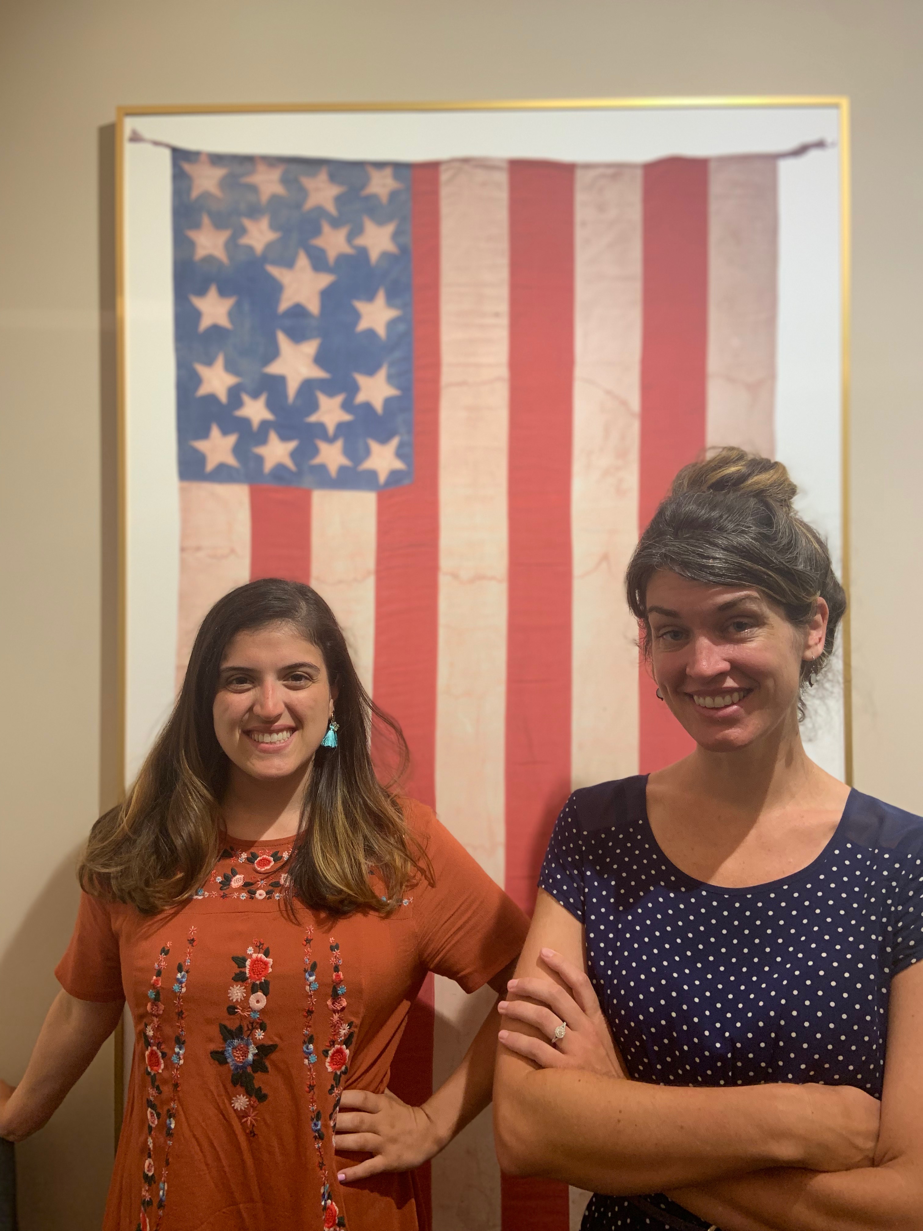Morgan and Cassidy standing with the abolitionist flag behind the front desk of the Gilder Lehrman Institute.