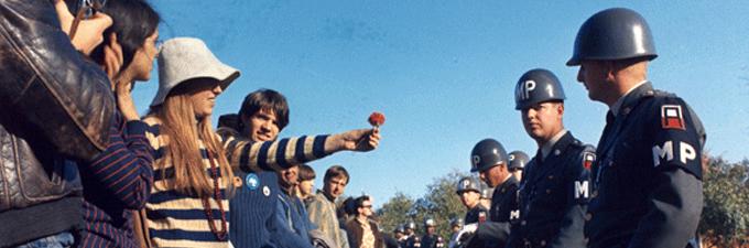 Photograph of a female demonstrator offering a flower to a military police officer, October 21, 1967. (National Archives and Records Administration)