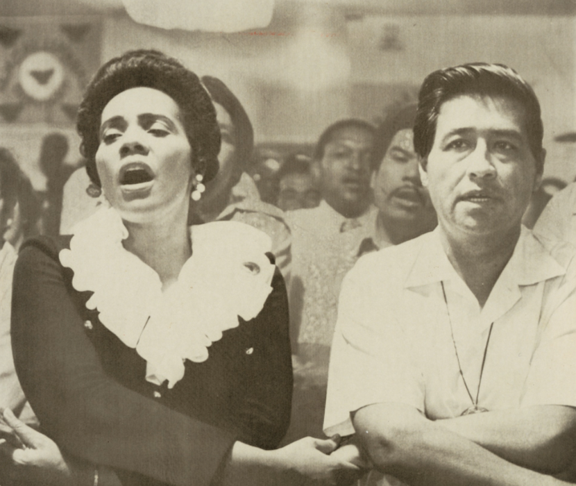 Photograph of Coretta Scott King and Cesar Chavez holding heads during a religious service