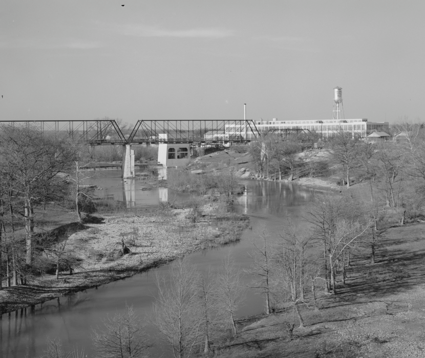 Black and white photograph from 1940 showing a river, bridge, and textile mills in New Braunfels, Texas