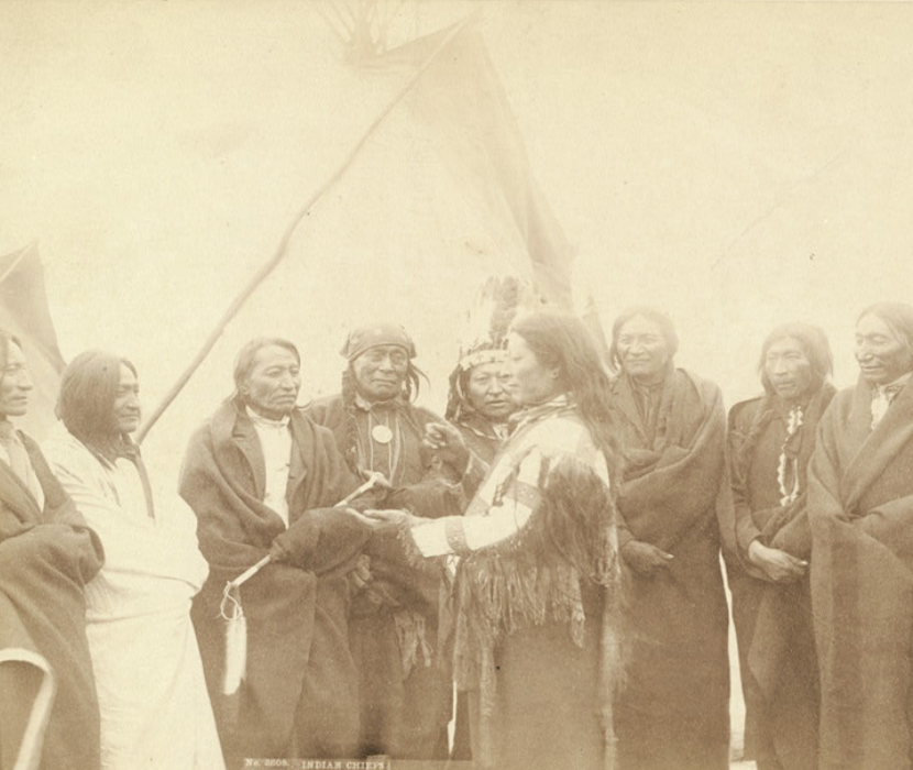A group photograph of Lakota chiefs standing in front of tipi.