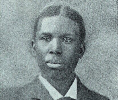 Portrait of Paul Laurence Dunbar, a young Black man, wearing a dark suit and tie and white shirt.