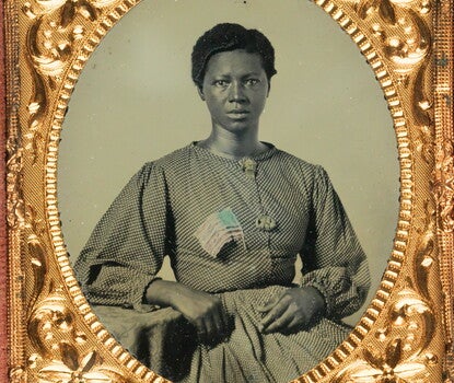 A Black woman wearing a polka-dot dress and wearing an American flag pin on her right breast.