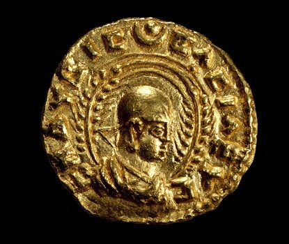 Obverse of coin with half-length bust of Ezanas right, crowned, holding stick or scepter, flanked by two wheat stalks, and Greek letters around the outside, the whole in a beaded circle