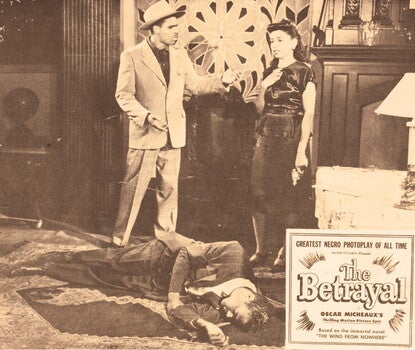 A lobby card for the movie "The Betrayal". The card is comprised of a black-and-white image of a man and woman standing in a room in front of another man lying on the carpet on the floor. The man on the floor appears to be dead. The woman is wearing a dark shiny dress and is holding a gun at her side in her left hand. Her right hand is resting on her chest and her face appears to be in a state of shock. The man standing next to her is wearing a light colored suit and hat and is extending his hand toward her