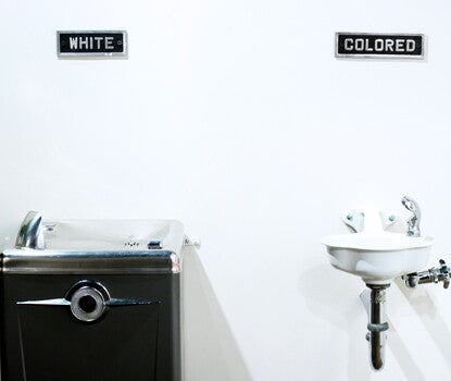 Two water fountains: at left, a larger water fountain labeled "white" and a smaller fountain labeled "colored." The labels appear above the fountains.