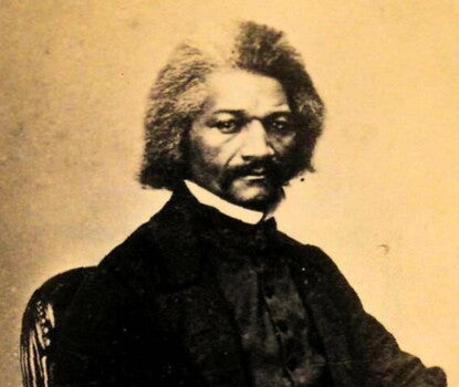 Image of man sitting and posing for a black and white photograph.