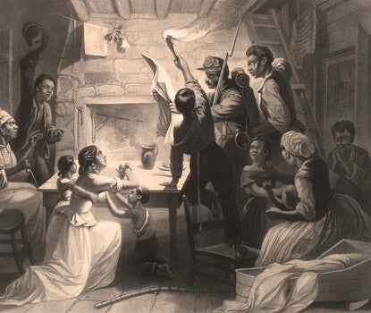 Black and white print of Black men, women, and children reading the news of their emancipation.