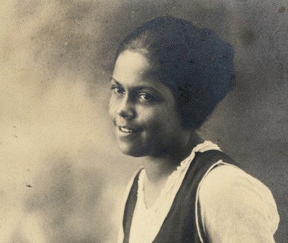A sepia photograph of Gwendolyn Bennett, a young Black woman, seated, wearing a dark jumper over a white t-shirt.