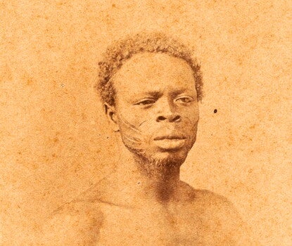 Sepia photographic portraits of a man and a woman; the woman is wearing a white shirt with checked trim and an earring; the man is bare-chested, with well-defined musculature. Both have traditional scarification on their cheeks.