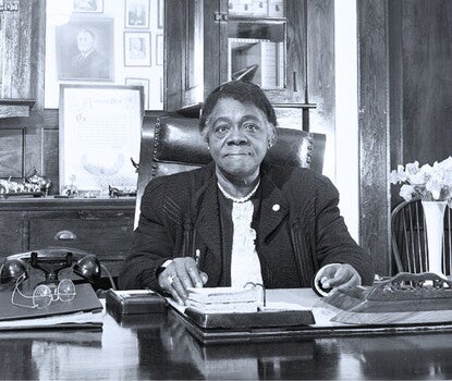 Mary McLeod Bethune seated at her desk in Bethune-Cookman College.