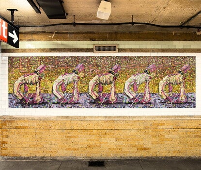 A tile mosaic in a subway station of drum majors in white uniforms dancing in formation.