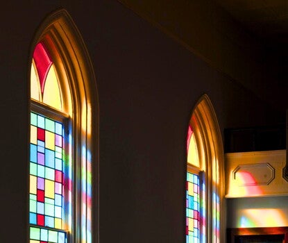 The interior of the Dexter Avenue Memorial Baptist church, with light streaming in through multicolored stained-glass windows.