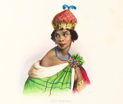 A Black woman wearing a gold, red, and blue crown, blue necklace, and a green checked royal robe.