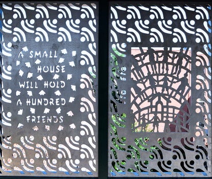 A color photograph of two panels of perforated metal, buildings and the sky visible through the perforations