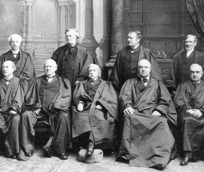 Justices of the Supreme Court, all white men, in black robes, five seated, and four standing.