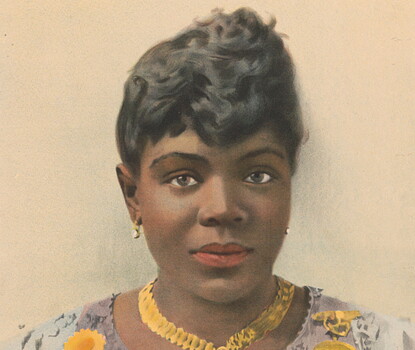 A hand-colored portrait of Sissieretta Jones, a Black woman also known here as The Black Patti and the Greatest Singer of Her Race, wearing a gold necklace and earrings and a white dress covered with medals and ribbons.