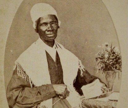 A black-and-white photograph of Sojourner Truth, seated, holding sewing materials in her hand; below her portrait is the phrase "I sell the shadow to support the substance."