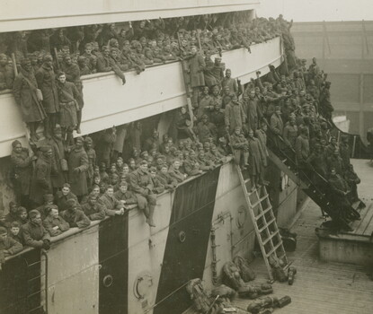 A black-and-white photograph of Black and white soldiers on decks of a large ship.