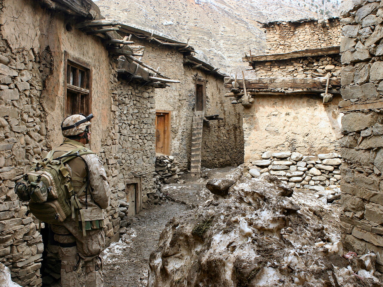 Soldier walking through alley between houses in desert terrain