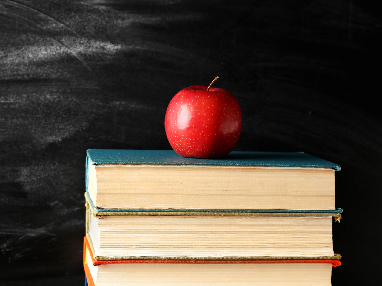 Apple on a stack of books in front of a chalkboard
