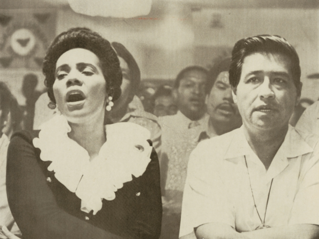 Photograph of Coretta Scott King and Cesar Chavez holding heads during a religious service