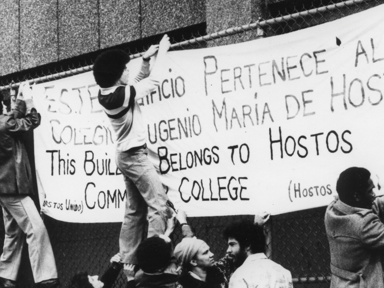 Student and faculty protestors hanging a banner at Hostos Community College