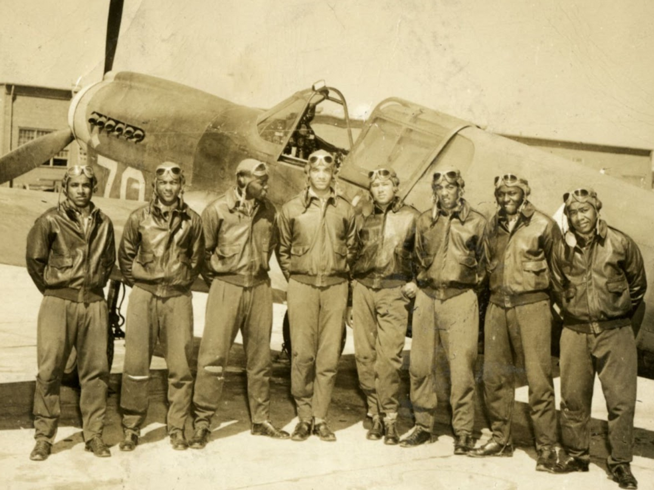 Group of WwII airmen posed by airplane at Tuskegee Army Airfield