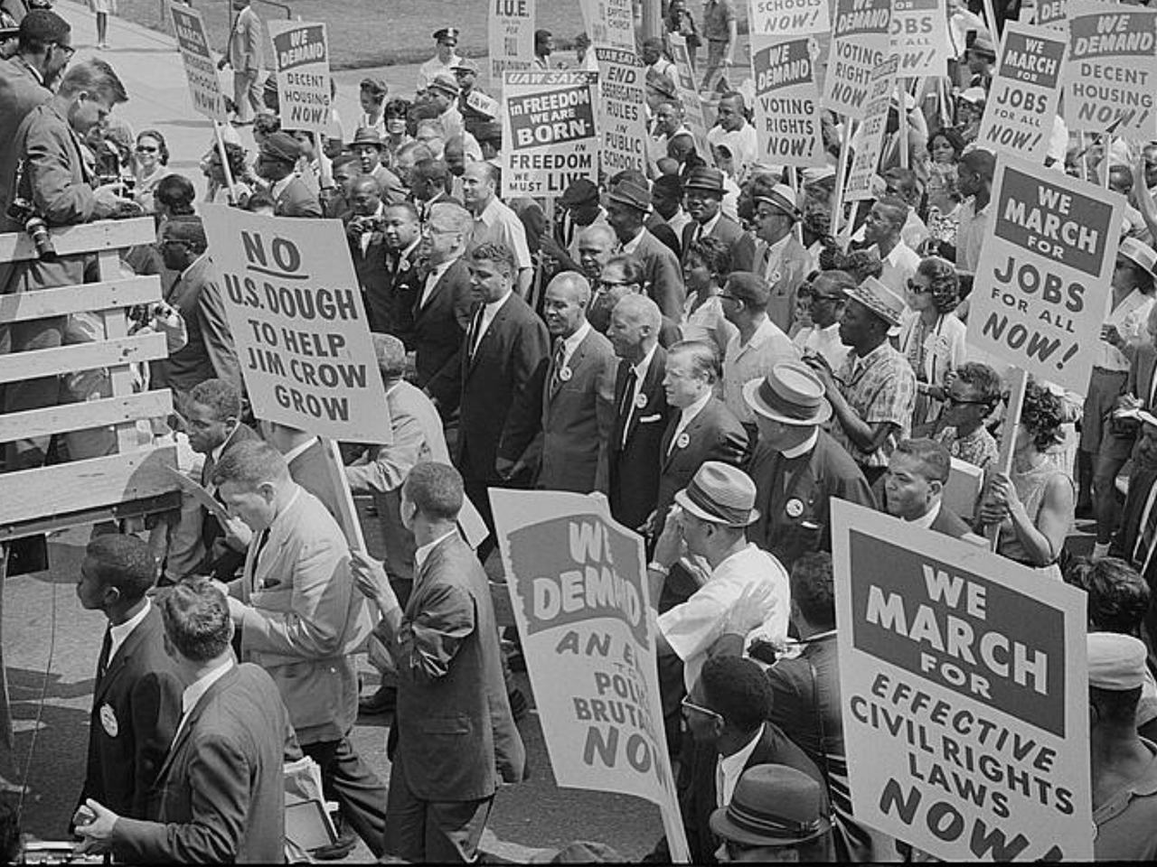 Photograph of civil rights leaders, including Martin Luther King, Jr., surrounded by crowds carrying signs.