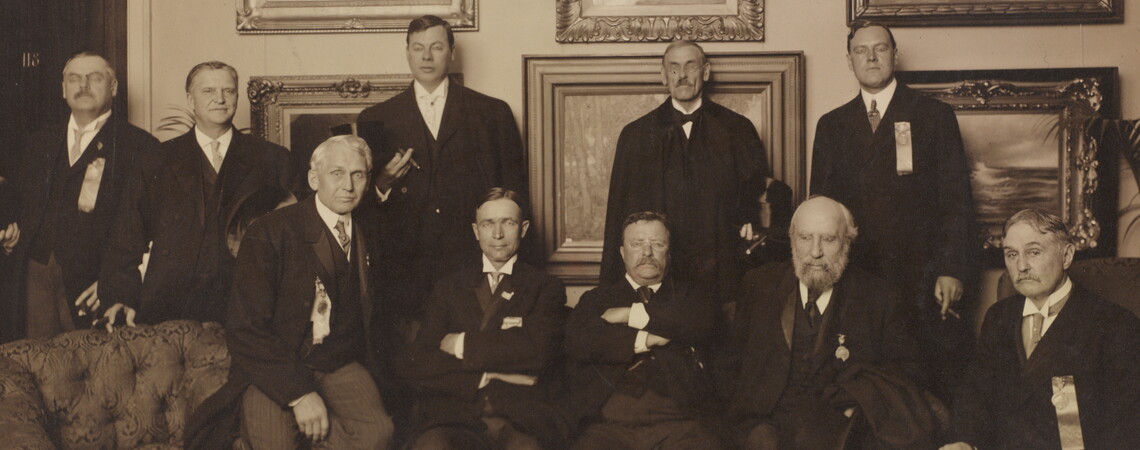 Photograph showing Theodore Roosevelt seated in center with nine other men.