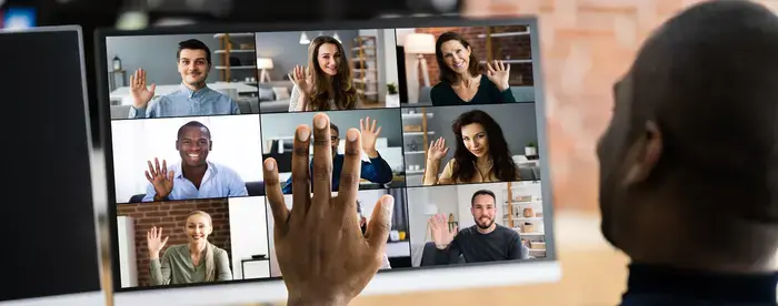 Man waving at computer with zoom session live and attendees waving back