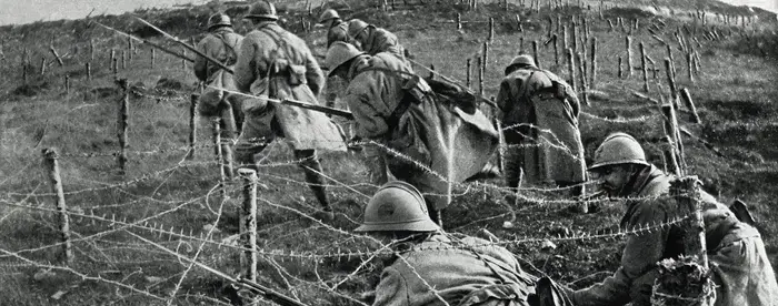 Soldiers crawling under barbed wire during World War I