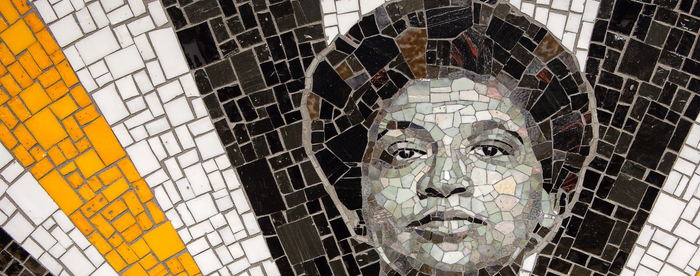 A mosaic featuring a black-and-white portrait of Audre Lorde surrounded by bursts of gold, white, and black tiles.