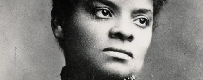 A portrait of Ida B. Wells. She is wearing a striped, high-necked dress and her hair is in a bun.  