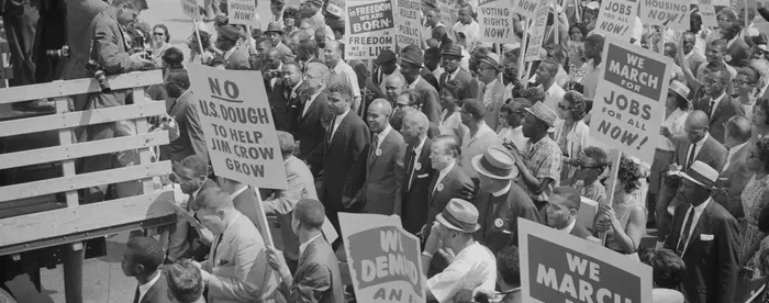 Photograph of civil rights leaders, including Martin Luther King, Jr., surrounded by crowds carrying signs.