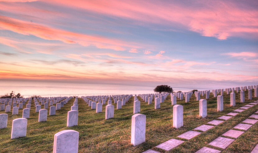View of graves at cemetery overlooking ocean at sunset
