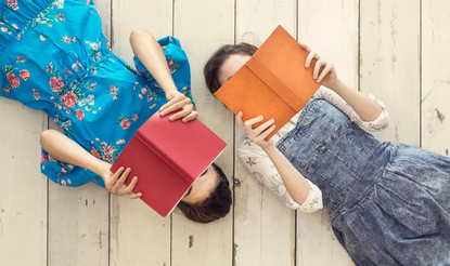View of two kids lying on the floor reading