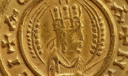 Obverse of coin with half-length bust of Ezanas right, crowned, holding a stick or scepter, flanked by two wheat-stalks, the whole in a beaded circle with Greek lettering around the outside.
