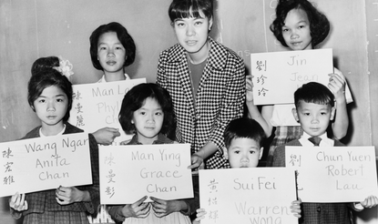 April Lou, teacher at PS 1, Manhattan, with six Chinese children, recent arrivals from Hong Kong and Formosa, who are holding up placards giving his or her Chinese name in ideographs and in transliteration. Photo by Fred Palumbo, 1964 (Library of Congress)
