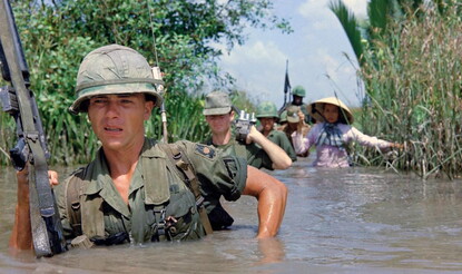 American soldiers wade through a canal in Vietnam