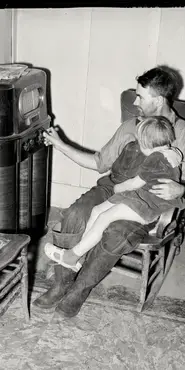 Photograph of father and daughter listening to a radio.