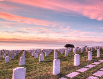 View of graves at cemetery overlooking ocean at sunset