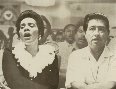 Photograph of Coretta Scott King and Cesar Chavez holding heads during a religious service