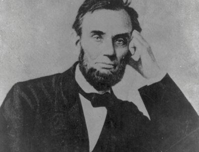 A black-and-white photograph of President Abraham Lincoln, seated, with his head resting on his upraised left hand