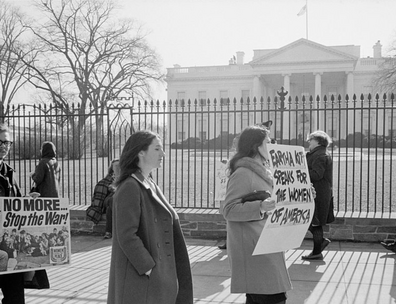A photograph of anti-Vietnam War demonstrators carrying signs, "No more...Stop the war!", "Eartha Kitt speaks for the women of America", and "Stop the draft", picketing in front of the White House.